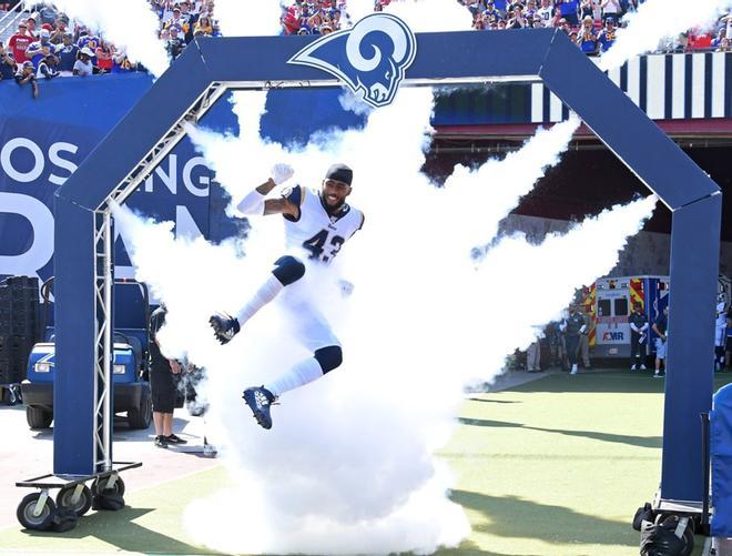 El safety John Johnson # 43 de Los Angeles Rams salta a través del humo mientras sale al campo para el juego contra los San Francisco 49ers en el Los Angeles Memorial Coliseum.