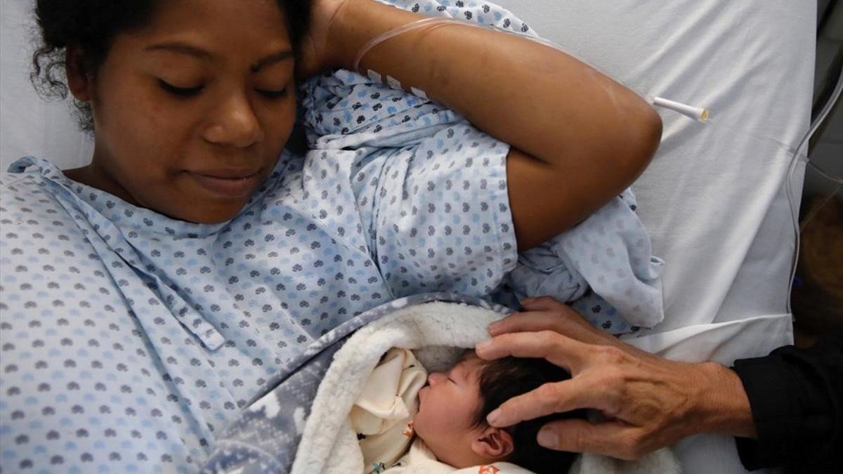 Una mujer hondureña que se dirigía a EEUU en una caravana migrante cuida de su recién nacido en un hospital en un hospital de la loclaiad mexicana de Puebla.