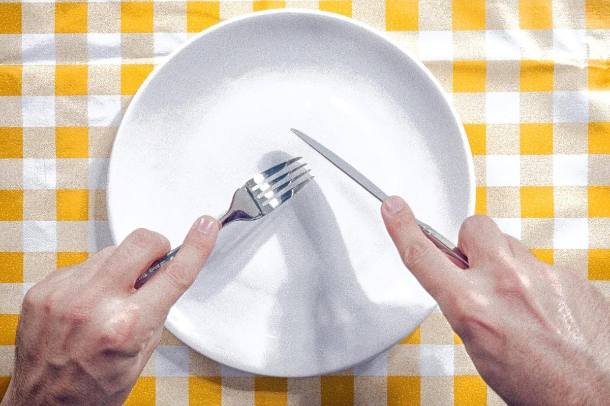 Imagen de una persona sosteniendo unos cubiertos con un plato vacío enfrente