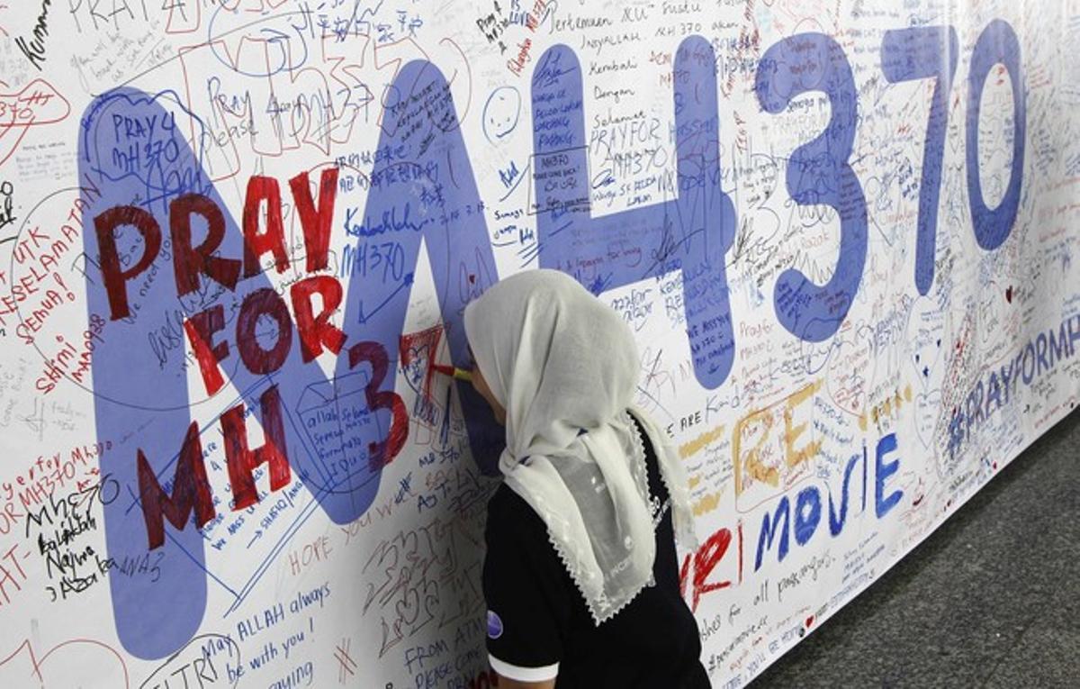 Una dona escriu un missatge en un mur dedicat al vol MH370 de Malaysia Airlines, aquest divendres a l’aeroport de Kuala Lumpur.