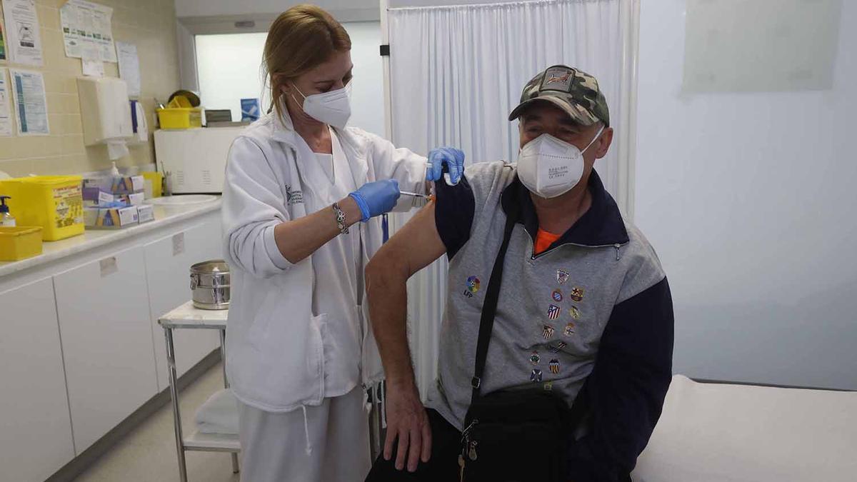 Una sanitaria vacuna con la tercera dosis a un paciente.