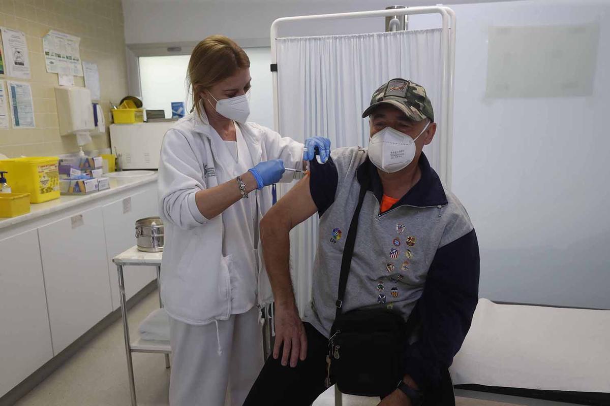 Una sanitaria vacuna con la tercera dosis a un paciente.