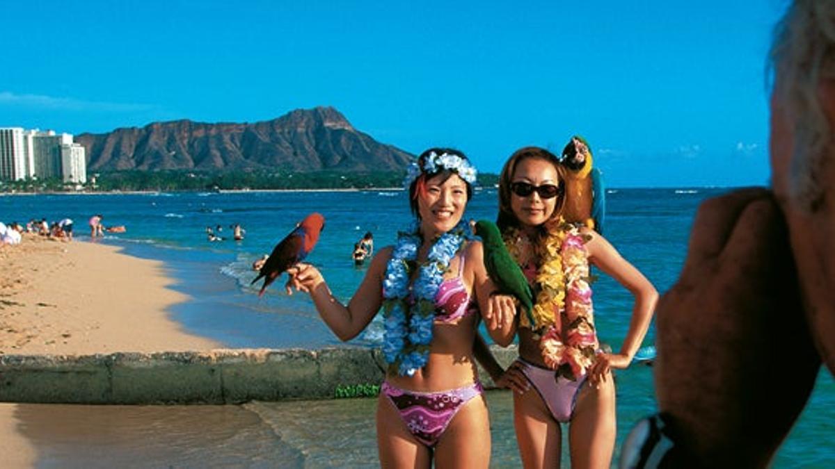 La playa de Waikiki, en Honolulu, es un reino de compras exclusivas, limusinas blancas y sugerentes