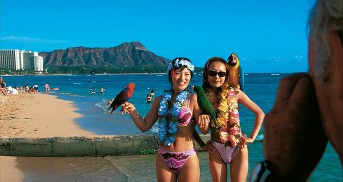 La playa de Waikiki, en Honolulu, es un reino de compras exclusivas, limusinas blancas y sugerentes
