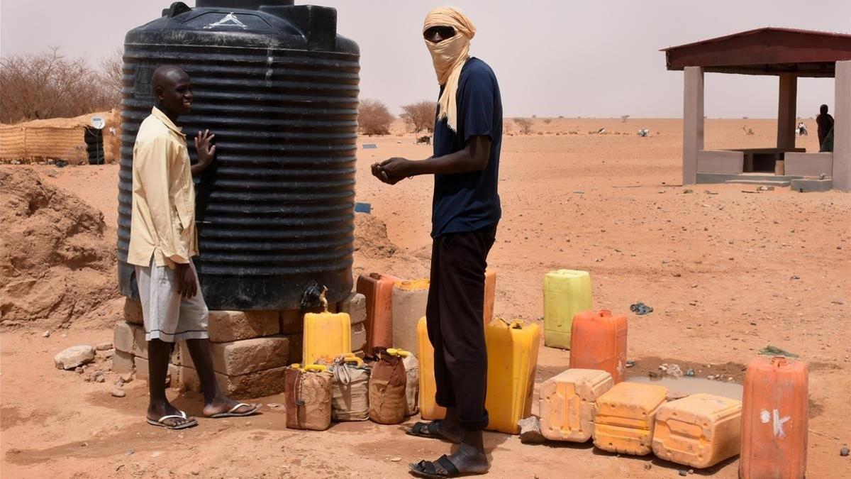 Dos refugiados recogen agua en un tanque en un campo de Níger.