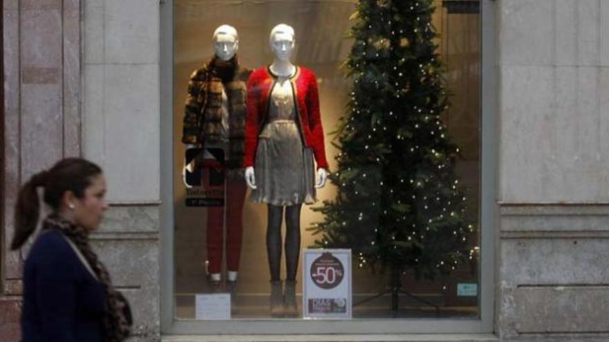 Una mujer pasa por delante de un escaparate adornado para Navidad.