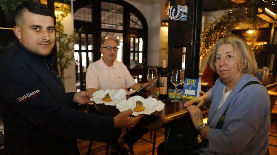 Alberto Albarrán sirve el pincho del restaurante El Dólar a Carmen Suárez y Francisco Javier González. | FERNANDO RODRÍGUEZ
