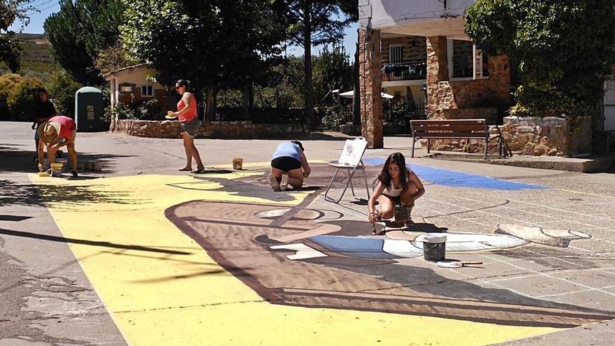 Un grupo de vecinos pinta un mural sobre el asfalto de la plaza de Villaflor. | Cedida