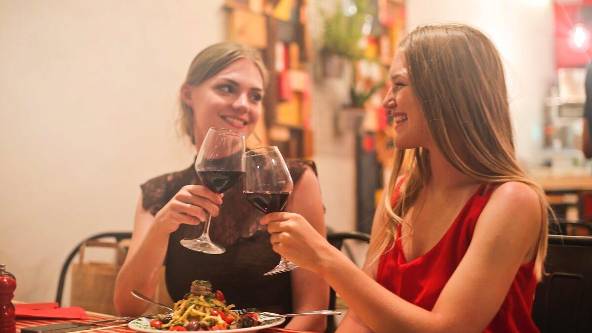 Dos chicas brindando con vino tinto