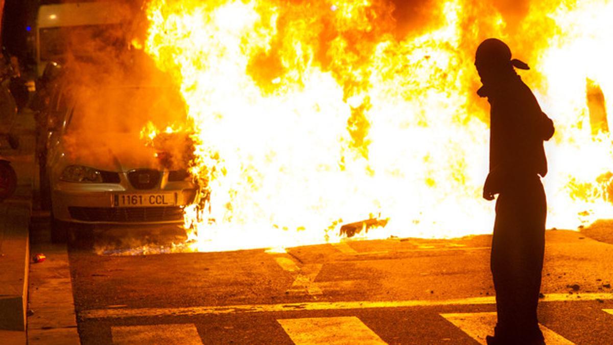 Un participante en los disturbios de Can Vies observa cómo arden los restos de un coche en la calle Sant Oleguer, el pasado 31 de mayo.