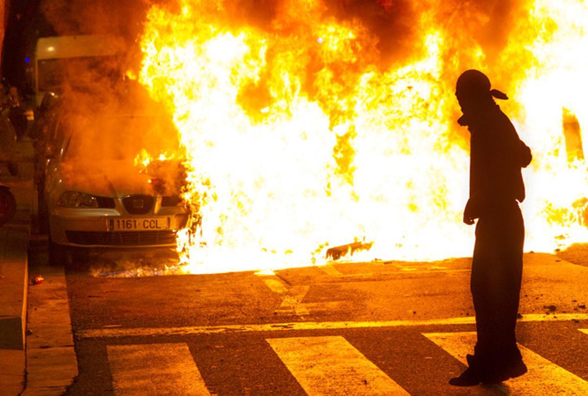 Un participant en els disturbis de Can Vies observa com cremen les restes d’un cotxe al carrer Sant Oleguer, el passat 31 de maig.