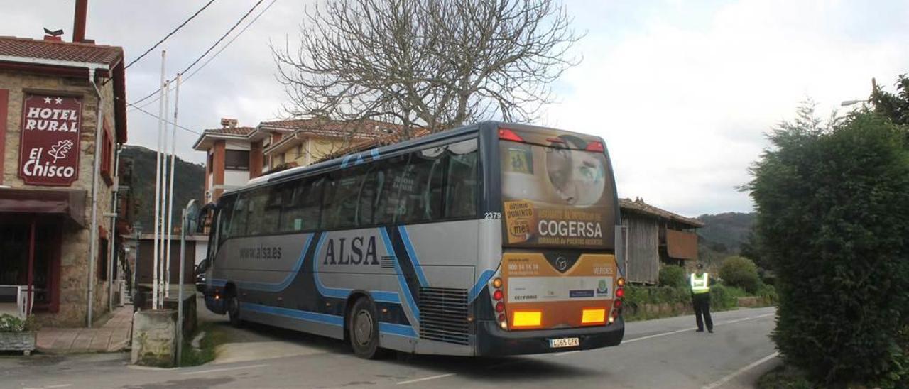 El autobús escolar, ayer, realizando una maniobra de giro en la parada antigua, ante la imposibilidad de dar la vuelta en la plaza, llena de turismos aparcados.