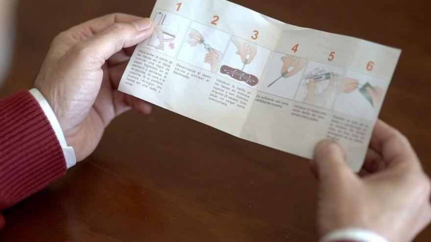 Un hombre consulta un folleto con información sobre el cribado de colon.