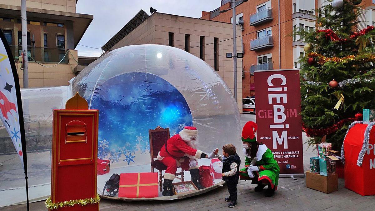 Un niño de Bonrepòs le da la mano al Papa Noel que está dnetro de la burbuja de plástico. | A. B.I.M.