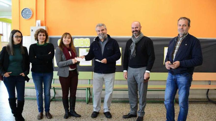 Jesús Portela (c), con el alcalde (2º d.) y los tres ediles, entrega el cheque a la directora del colegio. // G.N.