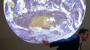 Un participant en la cimera del clima, davant de la bola del món que s’exhibeix en la trobada.