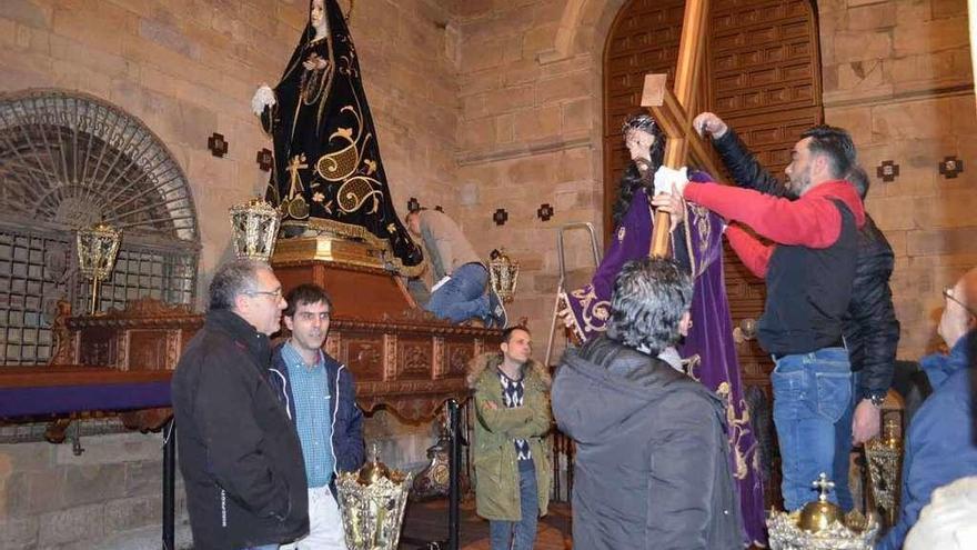 Varios cofrades se afanan en colocar la cruz sobre el Nazareno, mientras otros ultiman los detalles de la Dolorosa.