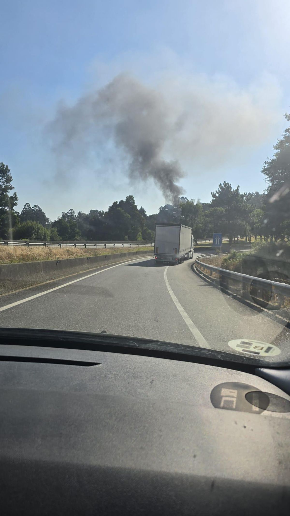 Columna de humo en la AP-9 en Vigo por el incendio de un coche que se extendió a la vegetación.