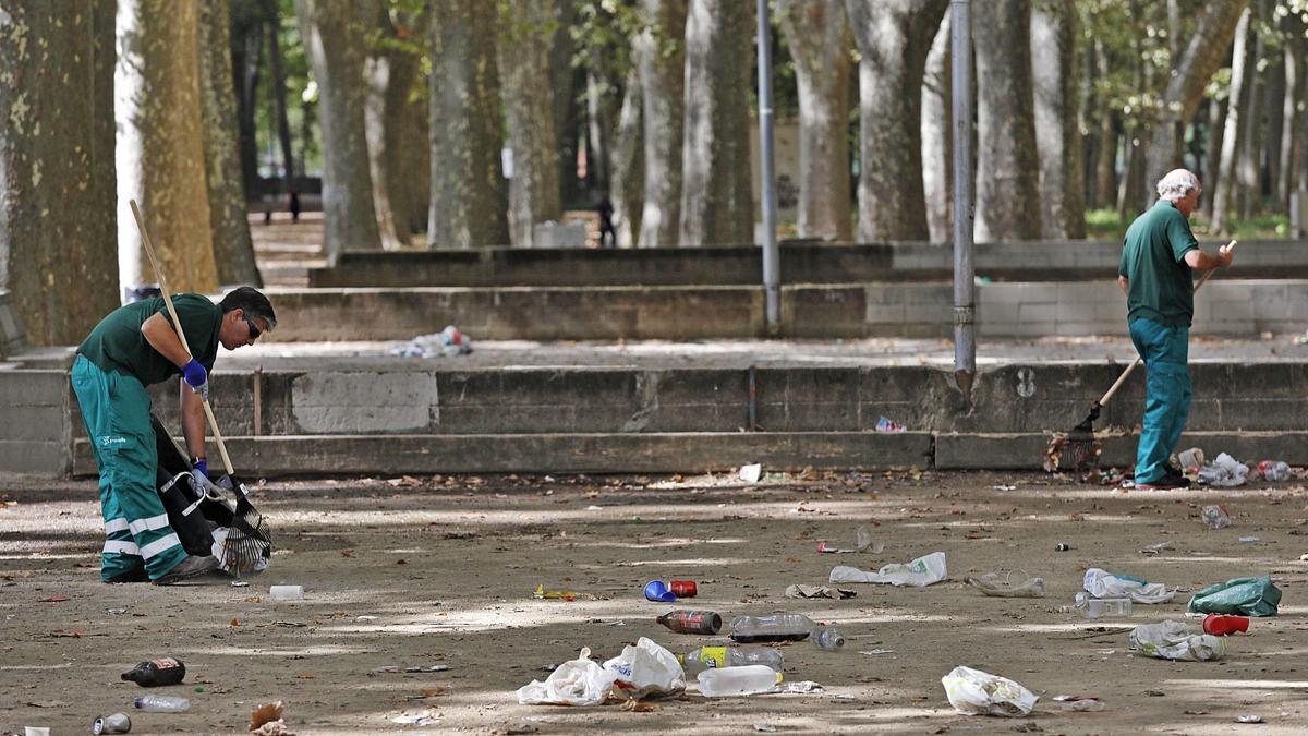 Operaris netejant el parc de la Devesa ahir, després del «botellon» de dijous a la nit. | ANIOL RESCLOSA