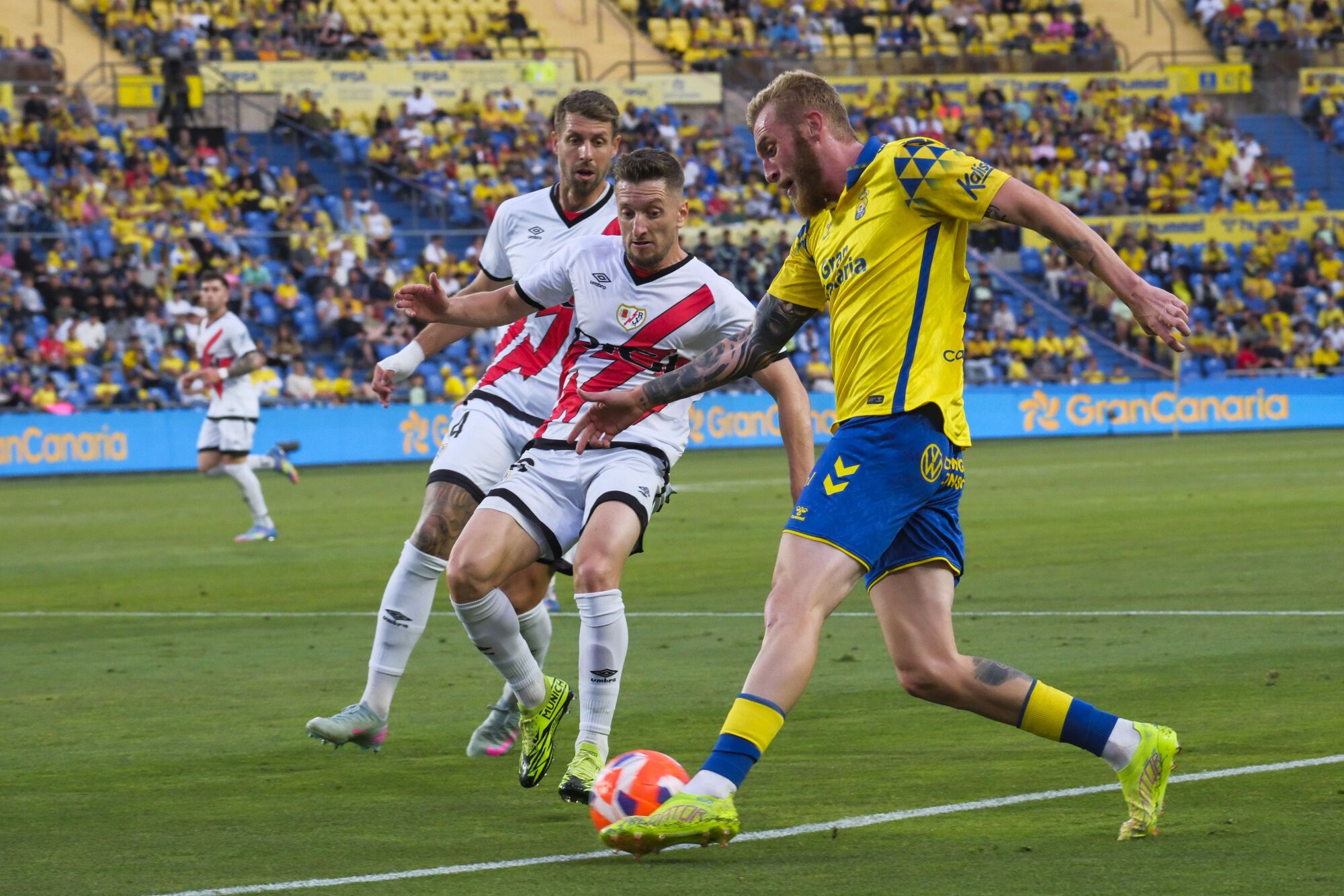 LAS PALMAS DE GRAN CANARIA, 09/05/2025.- El defensa del Rayo Vallecano Iván Balliu (c) presiona al delantero escocés de la UD Las Palmas, Oliver McBurnie (d), durante el encuentro correspondiente a la jornada 35 de Laliga EA Sports que disputan hoy viernes Las Palmas y Rayo en el Estadio de Gran Canaria. EFE / Angel Medina G.