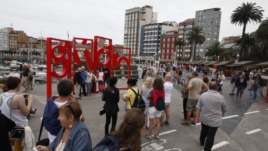 Turistas del crucero que ayer hizo escala en Gijón hacen cola ante las &quot;letronas&quot; para la foto.