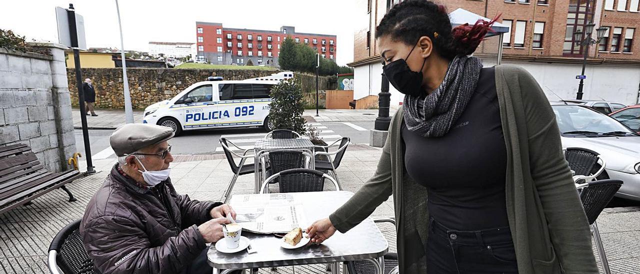 Nanci Lucía Agramonte sirve a José Antonio Pantiga en la terraza de su establecimiento hostelero de Colloto, en el límite entre los concejos de Oviedo y Siero. | Luisma Murias