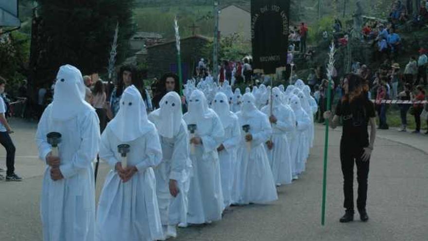 Los cofrades, vestidos con las tradicionales mortajas blancas, portan a hombros al Cristo en su urna.