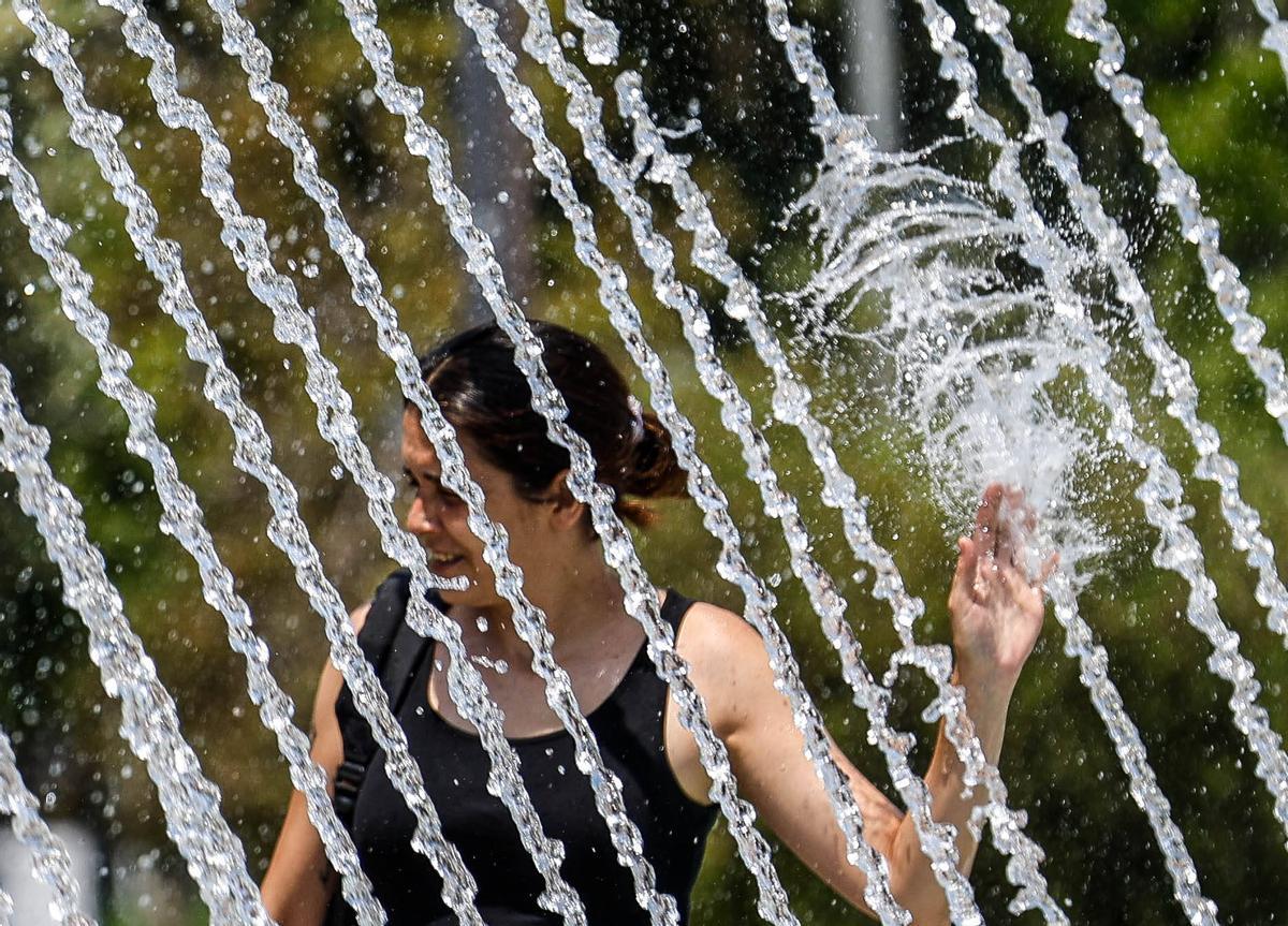 Una mujer se refresca en una fuente en el centro de València.