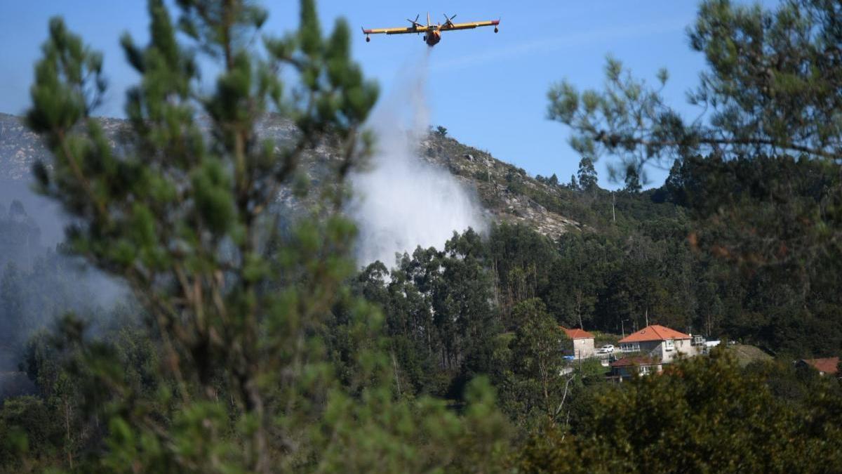 Un avión descarga agua esta mañana en el incendio de Augasantas, Cotobade.