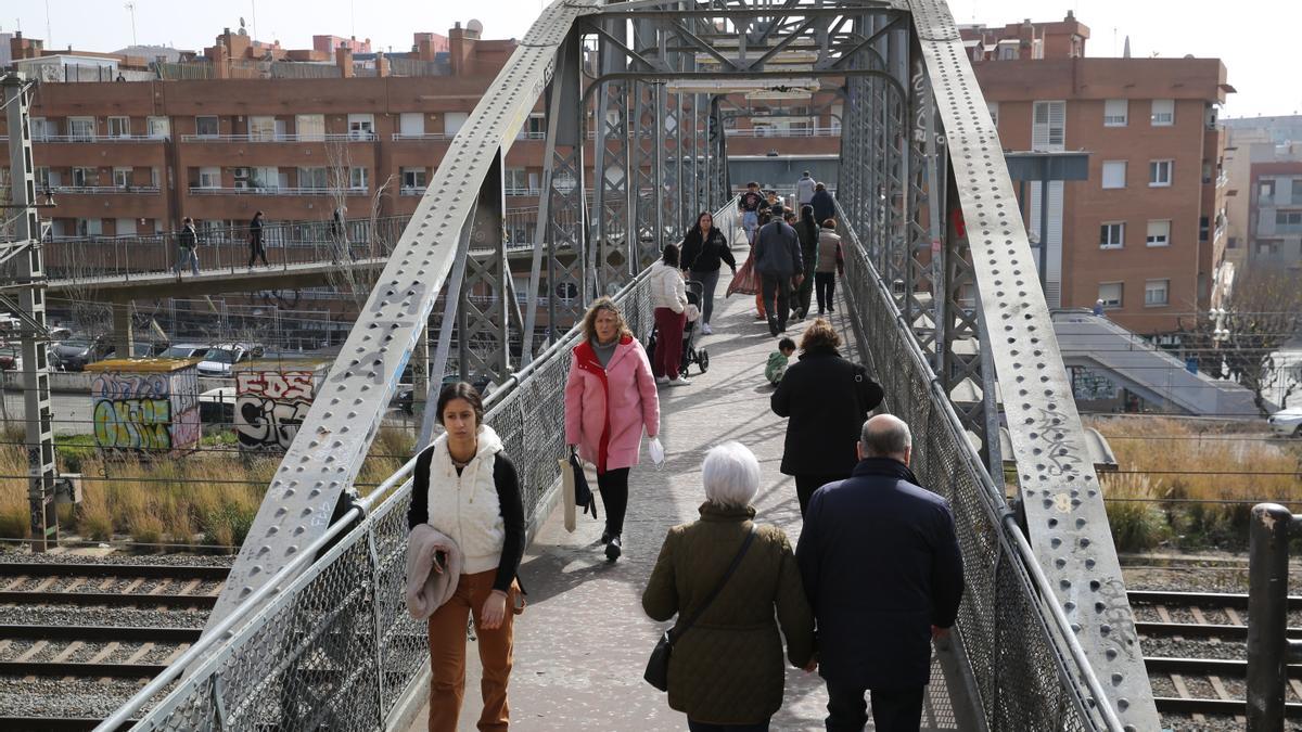 Vecinos de L'Hospitalet cruzan las vías de tren sobre el Pont d'en Jordà, que une los barrios de la Torrassa y Santa Eulàlia.