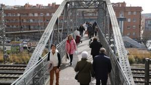 Vecinos de L’Hospitalet cruzan las vías de tren sobre el Pont d’en Jordà, que une los barrios de la Torrassa y Santa Eulàlia.