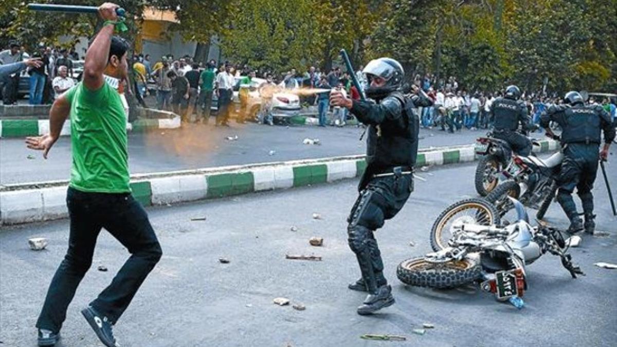 Un manifestante se enfrenta a un policía, hace un año en Teherán.