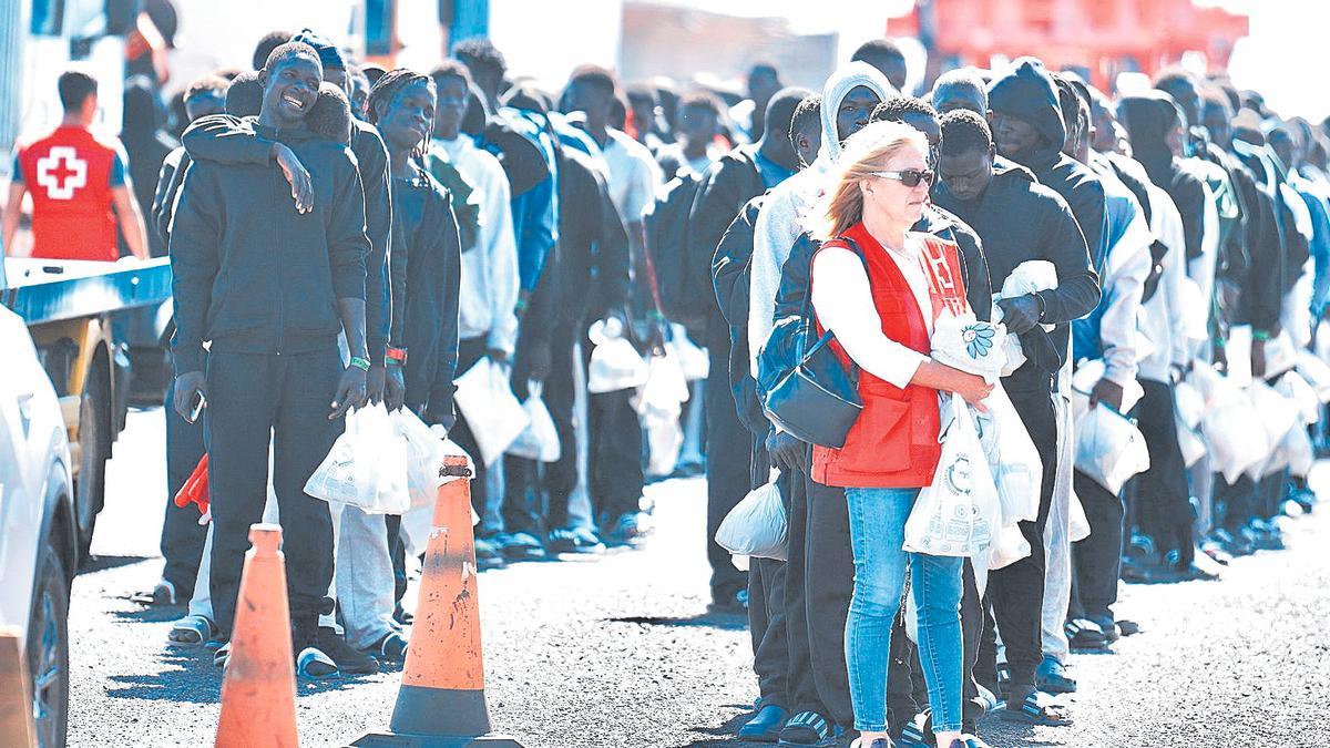 Una voluntaria de Cruz Roja al lado de decenas de migrantes antes de subir a un ferry hacia Tenerife desde El Hierro, ayer.