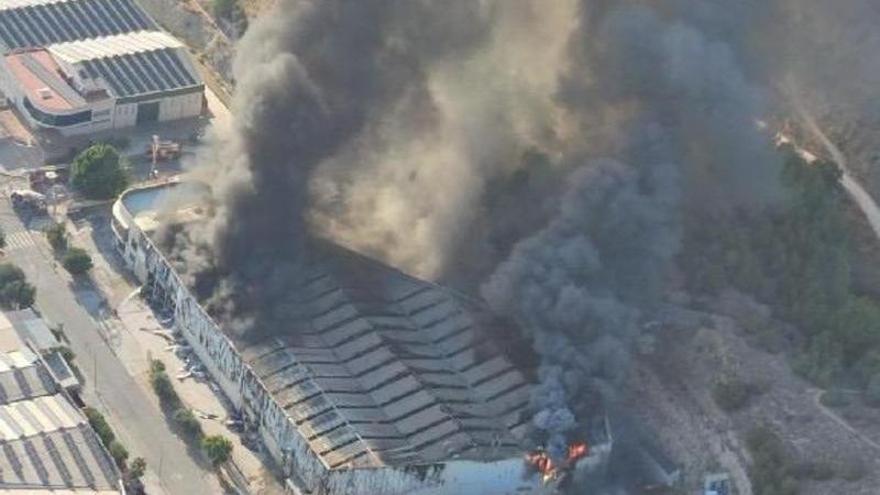 Un fuego en una nave industrial genera una gran columna de humo negro y causa un incendio forestal en Aspe