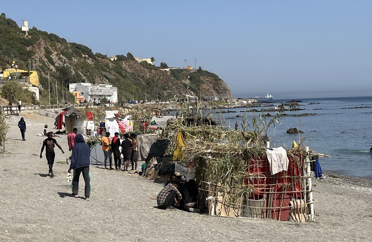 CEUTA, 09/08/2026.- Numerosos inmigrantes permanecen en la playa del Trampolín que se ha transformado en un asentamiento desde la entrada masiva registrada a finales de julio en la ciudad Ceuta. EFE/Reduan