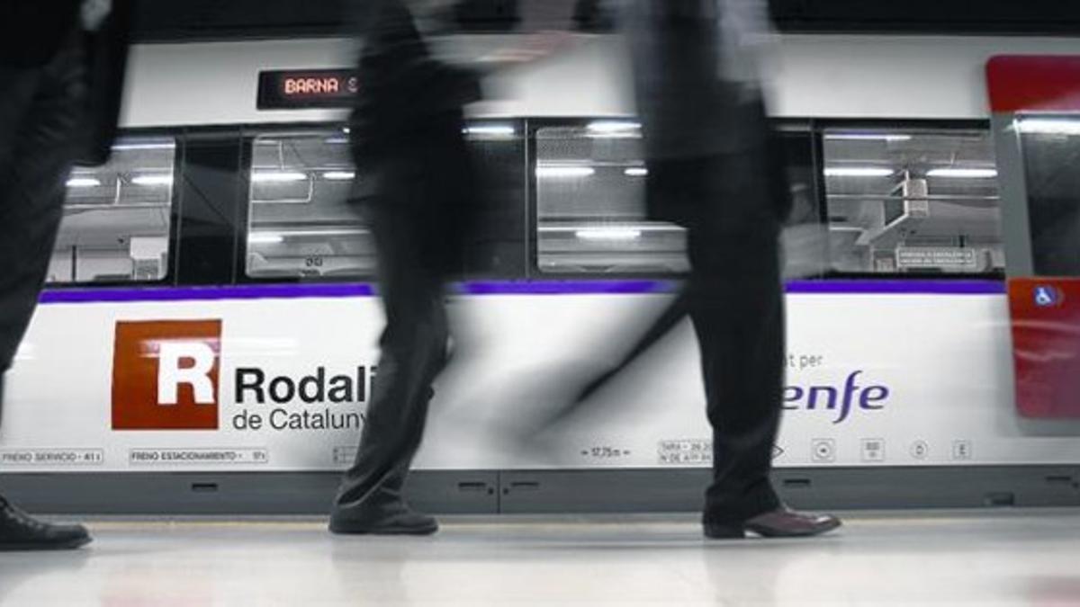Varios pasajeros descienden de un tren de Rodalies en la estación barcelonesa de Sants.