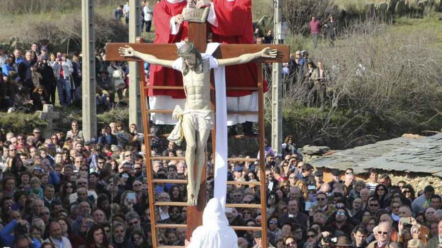 Acto del Descendimiento de Jesús observado por numerosas personas y, a la derecha, traslado del paso Cristo en la Urna llevado a hombros por los cofrades.