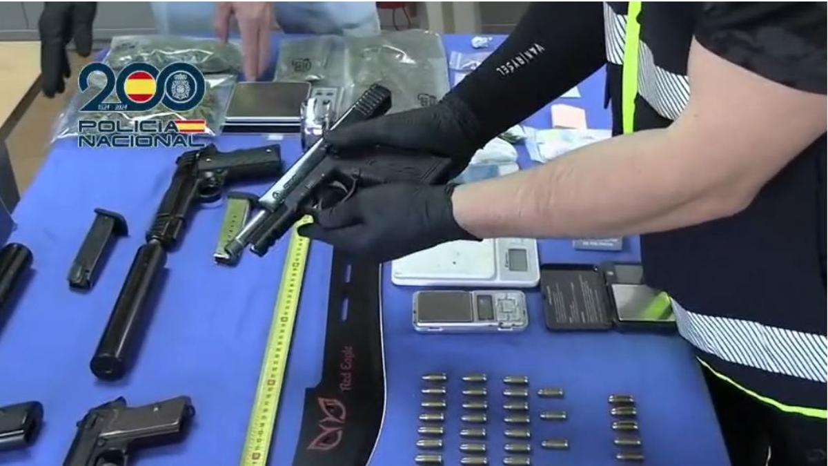 Un policía sostiene una de las cuatro pistolas del miembro de los Trinitarios.