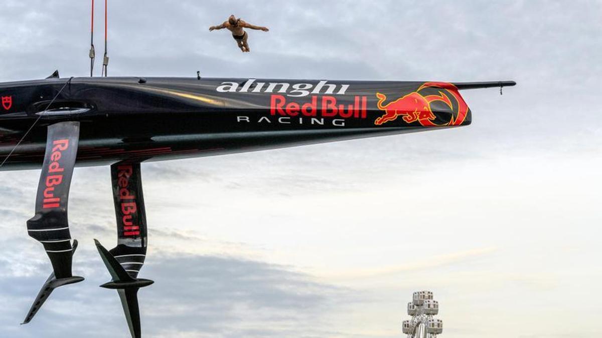 Un atleta de Red Bull salta desde el barco AC75 de la Copa América de vela en el estreno de la base del equipo suizo en el Port Vell de Barcelona.