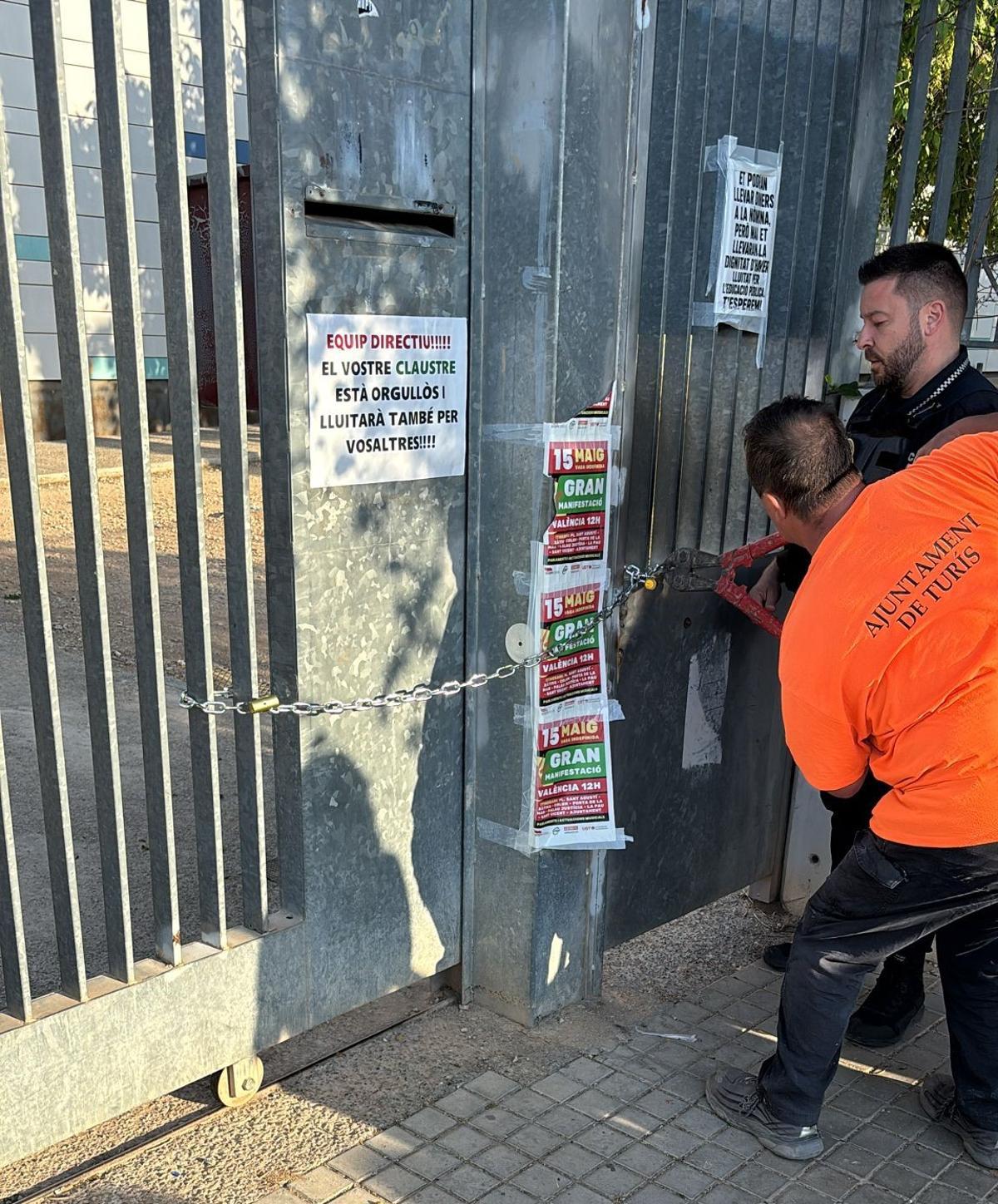 Un agente intenta cortar la cadena con una cizalla par permirir el acceso al centro.