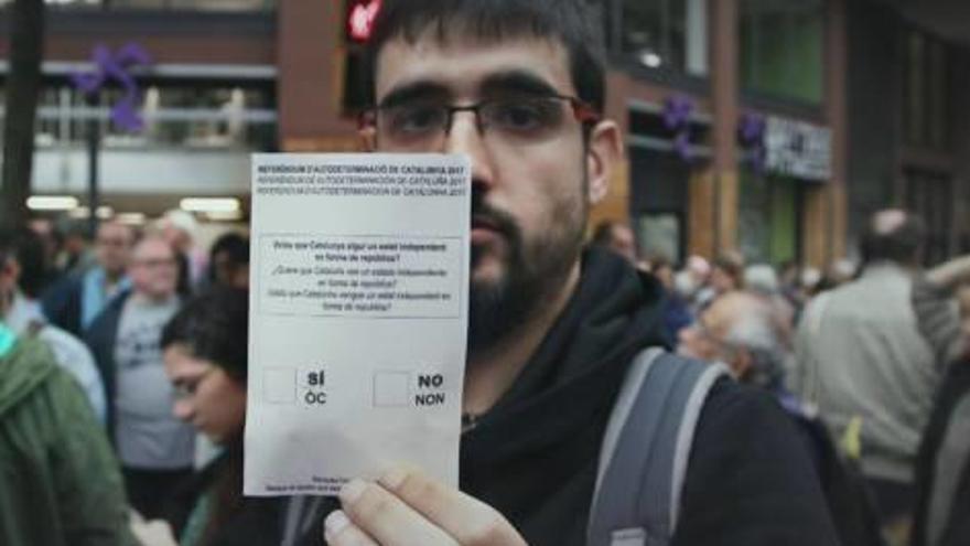 Un ciutadà mostra la papereta per votar el dia 1 d&#039;octubre de l&#039;any passat.