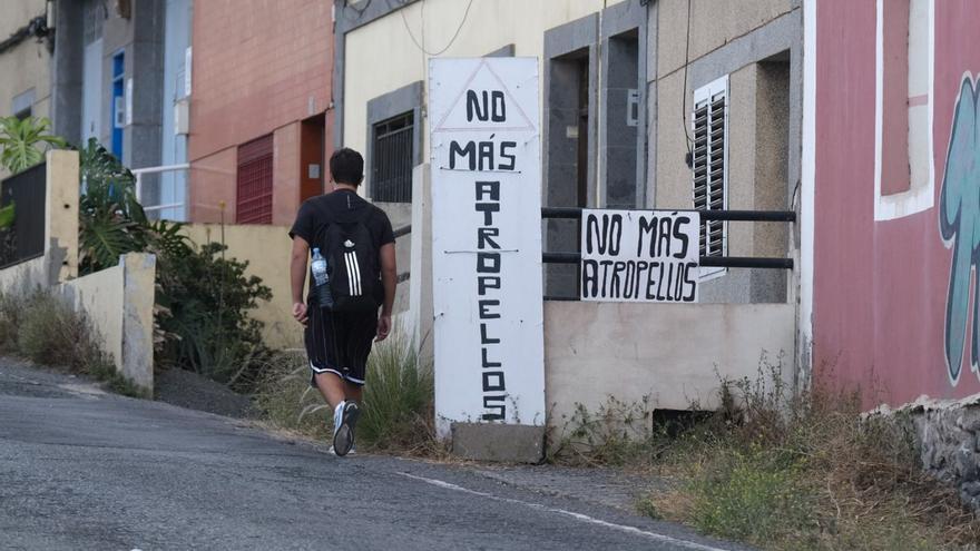 Un joven camina junto a un cartel de ‘No más atropellos’ en Almatriche.