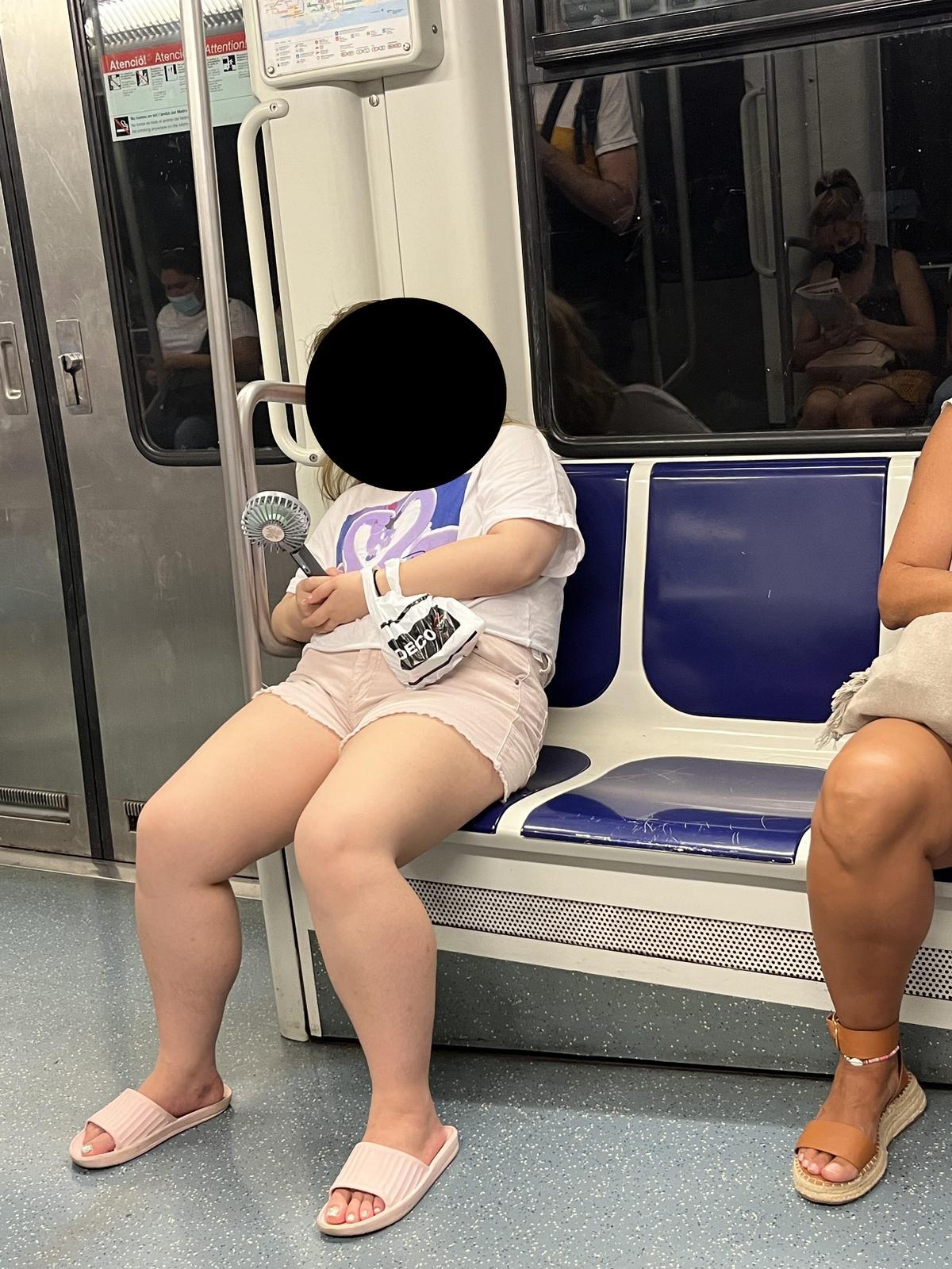 Una mujer sostiene un ventilador portátil en la L1 del metro de Barcelona.