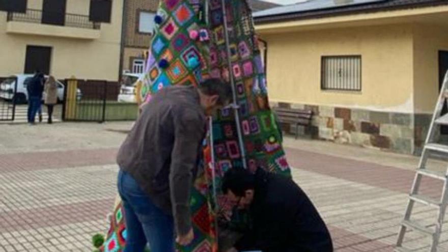 Dos vecinos colocando el árbol de ganchillo en la plaza. | E. P.