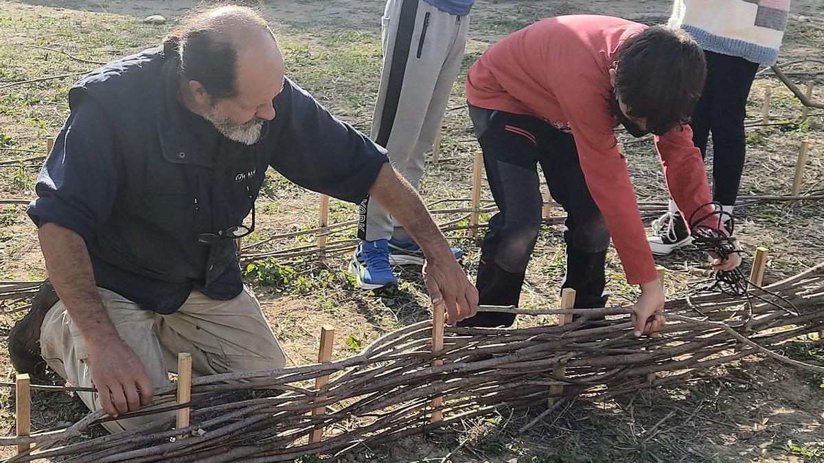Juan García ayuda a un alumno en la construcción de uno de los bancales del huerto escolar ecológico.