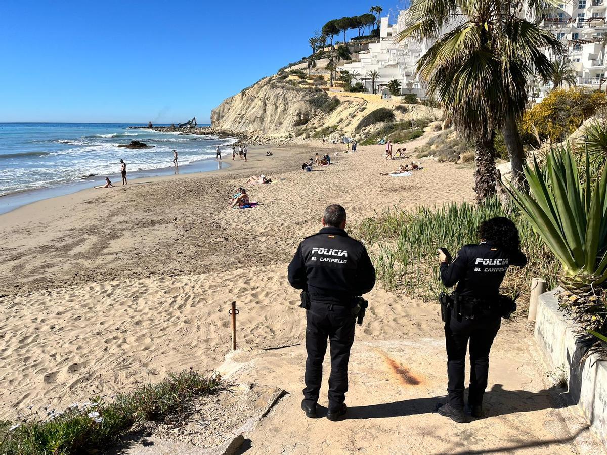 Dos polícias locales, este martes en Cala Lanuza, con bañistas en el arenal
