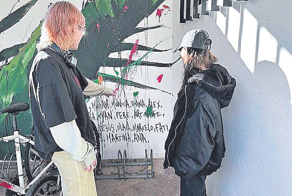 Isabella López, Cyan Capilla, alumnas señalando la firma en el mural.