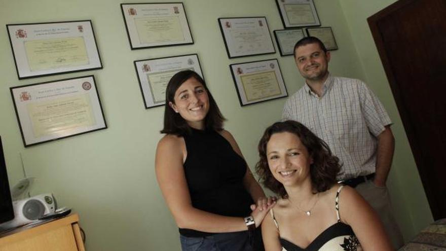 Por la izquierda, Ana, Cristina y Carlos, los hermanos Allende Prieto, junto a los títulos académicos de todos ellos en el piso de sus padres en Gijón.