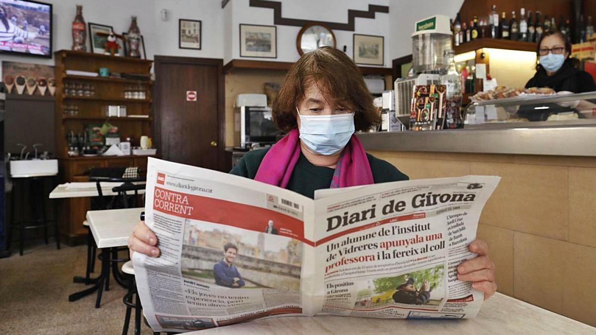 Una clienta llegint el diari en una cafeteria de la ciutat de Girona.