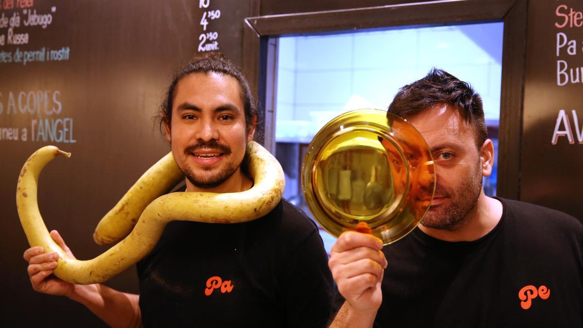 Paco Benítez y Pedro Baño, con un plato de Duralex, entre las pizarras de la Fonda Pepa, en Gràcia.